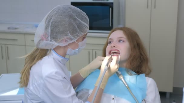 Ortodoncista cubriendo gel especial en dientes de mujer y secándolo en odontología. — Vídeo de stock