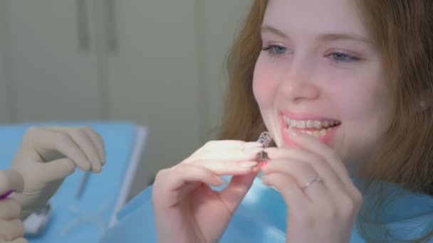 Médico ortodoncista instalando frenos transparentes de silicona en los dientes de las niñas. — Vídeo de stock