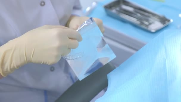 Médico ortodoncista pone frenos de silicona en bolsa de cremallera en odontología, primer plano de las manos. — Vídeo de stock