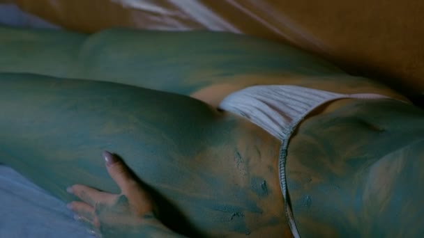 Procedimiento de envoltura con arcilla azul para mujer en el salón de spa, primer plano del cuerpo. — Vídeos de Stock