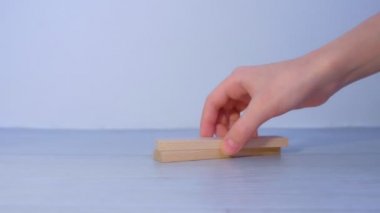 Düz tahta bloklardan bir kule inşa eder ve onları birbiri üstüne yığar..