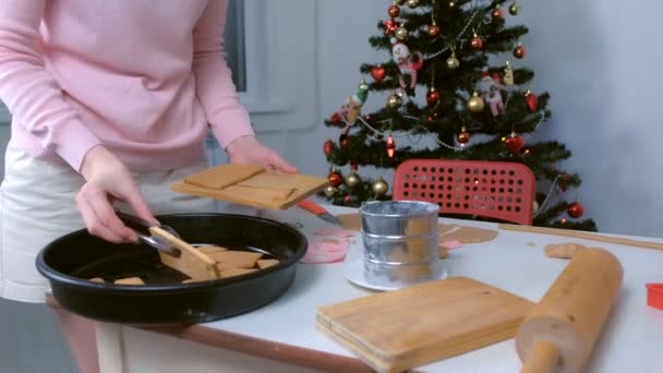 Vrouw zet delen van gember gefokt huis op houten plank met behulp van tangen, handen close-up. — Stockvideo