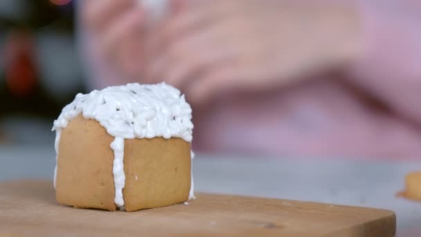 Frau schmückt Lebkuchenhaus mit zuckersüßem Zuckerguss, Hände in Großaufnahme. — Stockvideo