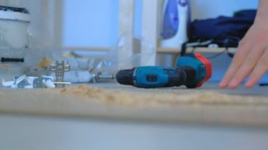 Adam yonga tahtasını delmeye hazırlanıyor, mobilya yapıyor, elleri kapalı..