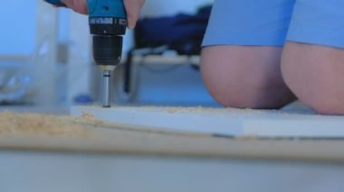 Menteşe yapmak için gardırop kapısında delik açan bir adam mobilya yapıyor..