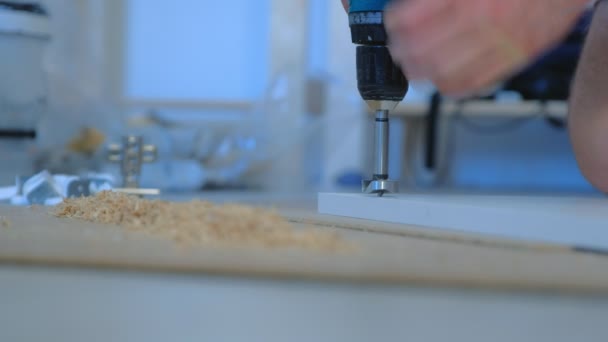 Man drills a round hole in the chipboard making furniture wardrobe door. — Stock Video