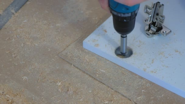 Man drilling round hole in chipboard wardrobe door for hinges making furniture. — Stock Video