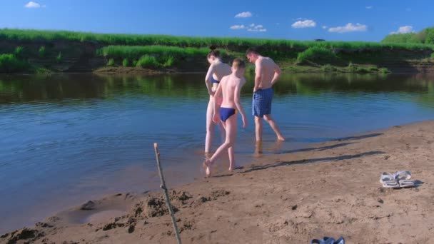 Nogi rodziny w strojach kąpielowych w rzece spacerując w wodzie w letni ciepły dzień. — Wideo stockowe