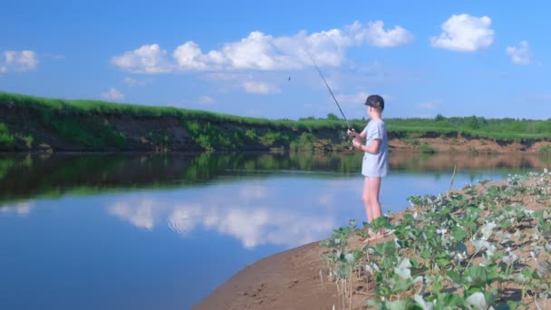 10 대 소년은 여름 화창 한 날 자연에서 물매를 사용 해 강에서 낚시를 하고 있습니다.. — 비디오