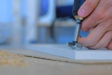 Adam yonga tahtasına yuvarlak bir delik açıyor. Mobilya gardırobu kapısı yapıyor..