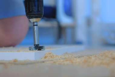 Menteşe yapmak için gardırop kapısında delik açan bir adam mobilya yapıyor..