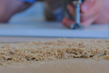 Marangoz atölyesinde ahşap talaşı, yonga tahtasında kapı menteşesi için adam delme deliği.