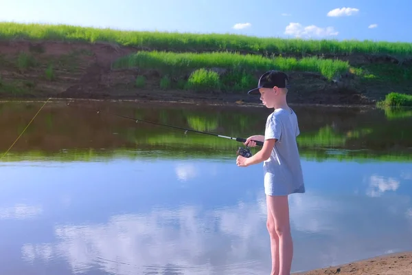 Niño niño está pescando en el río usando varilla giratoria en verano día soleado en la naturaleza. —  Fotos de Stock