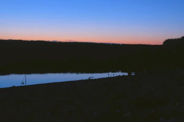 Schöner rosafarbener Sonnenuntergang in der Natur über dem Fluss, Steigungshimmel von blau nach rosa. — Stockfoto