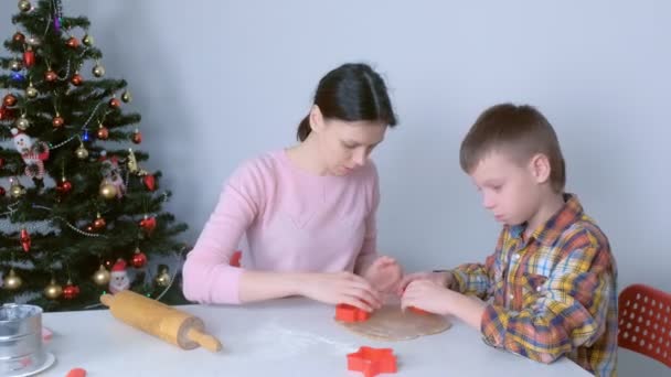 Mamá e hijo están haciendo galletas de jengibre de Navidad cortando de masa. — Vídeo de stock
