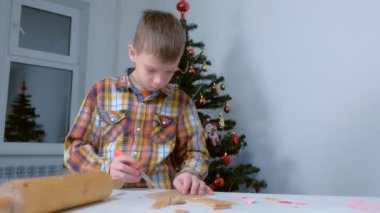 Çocuk Noel ağacı arka planında hamur keserek zencefilli kurabiye yapıyor..