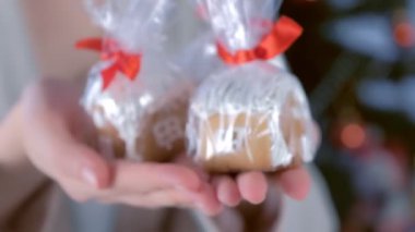 Noel için paketlenmiş zencefilli kurabiye evleri kadınların elleri ağaçta..
