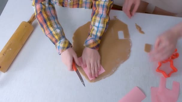 Мати і син вирізають деталі для імбирного будинку з тіста руки крупним планом . — стокове відео