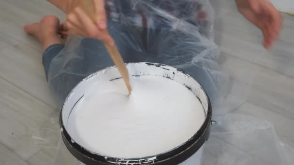 Vrouwen handen mengen een gallon grijze verf met houten verf roerstokje. — Stockvideo