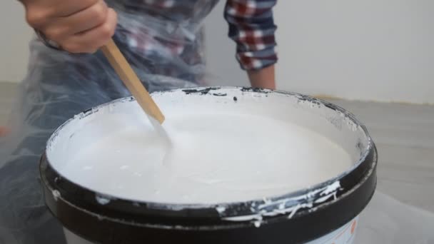 Mãos femininas misturando um galão de tinta cinza com pau de madeira. — Vídeo de Stock