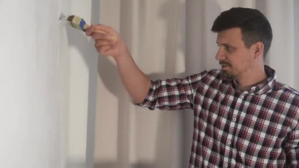 Porträtt av man hus målare målning vägg med pensel gör renovering, DIY. — Stockvideo