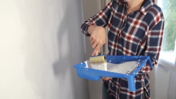 Γυναίκα σπίτι ζωγράφος τοίχο ζωγραφική χρησιμοποιώντας βούρτσα κάνει ανακαίνιση, χέρι closeup. — Αρχείο Βίντεο