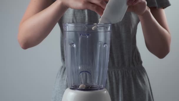 Kobieta wkłada migdały do miksera, aby przygotować mleko migdałowe, zbliżenie w zwolnionym tempie. — Wideo stockowe