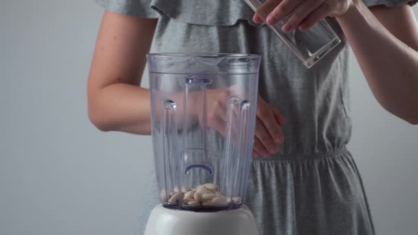 Frau gibt Mandeln und Wasser in einen Mixer, um Mandelmilch in Zeitlupe zuzubereiten. — Stockvideo