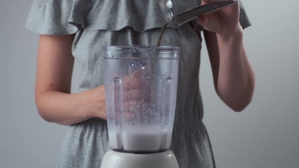 Frau kocht Smoothies und legt Chia-Samen in Mixer-Tasse auf Mandelmilch. — Stockvideo