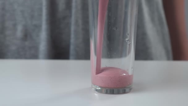 Vrouw schenkt aardbeien smoothies in glas uit blender cup, closeup view. — Stockvideo