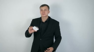 Siyah takım elbiseli sihirbaz hile yapıyor, kartları havaya fırlatıp yakalıyor..