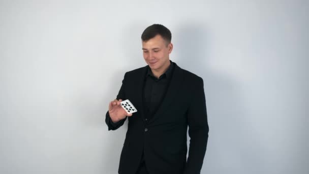 Goochelaar in zwart pak is het maken van truc, gooien en vangen van kaarten in de lucht. — Stockvideo