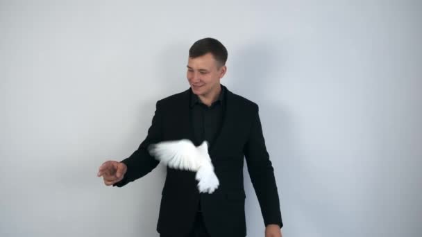 Kouzelník dělá trik s bílým holubím ptákem, který létá z jedné ruky do druhé. — Stock video
