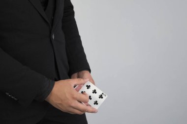 Sihirbazın yakın çekimleri gri arka planda kart değiştirerek numara yapıyor..