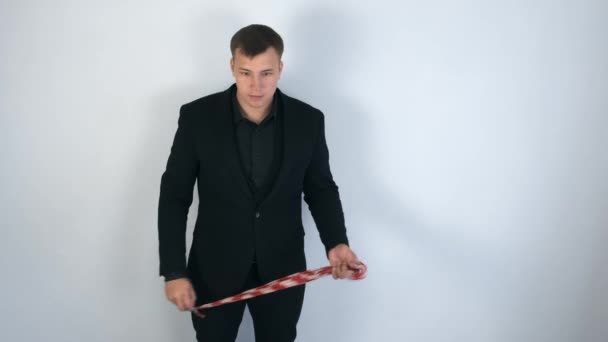 Magikern i svart kostym visar trick gör metall stick från huvudduk. — Stockvideo