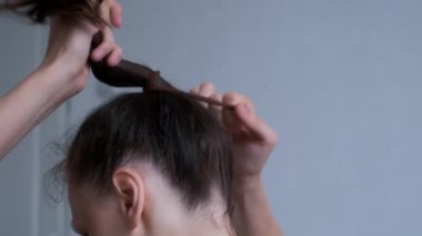 Kadın saçını bağlıyor. Beyaz arka planda at kuyruğu yapıyor..