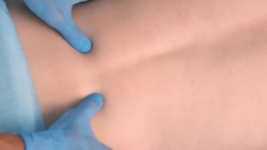 Eldivenli adam, kadını akupunktur için hazırlıyor. Sırtına masaj yapıyor..