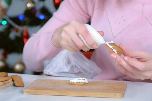 Femme fait maison de pain d'épice reliant les détails avec sucre glaçage sucré. — Photo