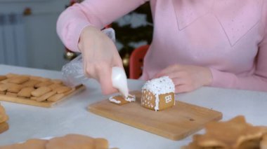 Kadın zencefilli kurabiye evini şekerli kremayla süslüyor..