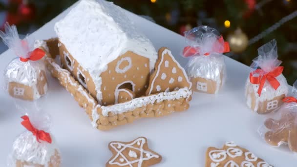 Μελόψωμο σπίτια και μπισκότα σε πακέτο για τα Χριστούγεννα σε φόντο δέντρο. — Αρχείο Βίντεο