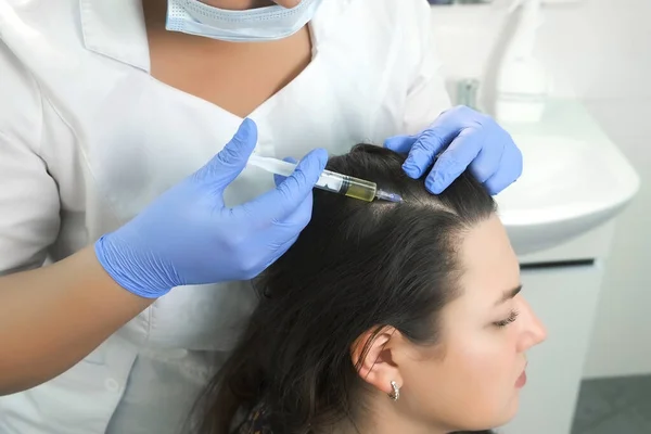 Doctor trichologist makes injections in womans skin on head for hair growth. Stock Photo