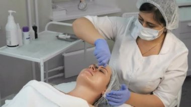 Kozmetik uzmanı kadın yüzüne şırınga kullanarak sarı kabuk bağlıyor..