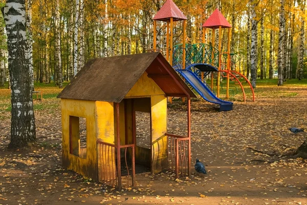 Громадський майданчик для дітей з гіркою та маленьким будинком в осінньому міському парку . — стокове фото