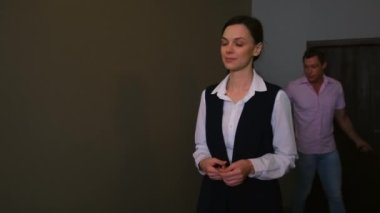 Kadın otel müdürü koridorda yürür ve çift için oda açar..