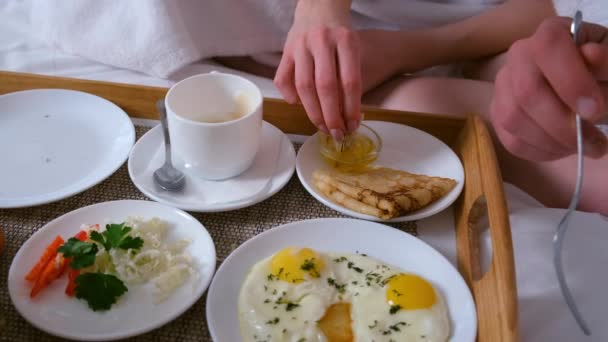 Paar frühstückt gemeinsam im Hotelbett, hölzerne Tablett-Nahaufnahme. — Stockvideo
