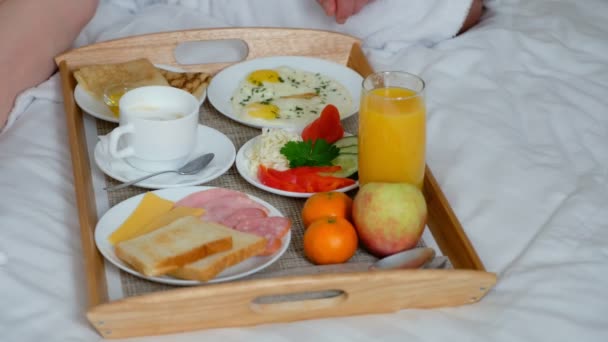 Couple prenant un petit déjeuner ensemble au lit à l'hôtel, plateau en bois gros plan. — Video