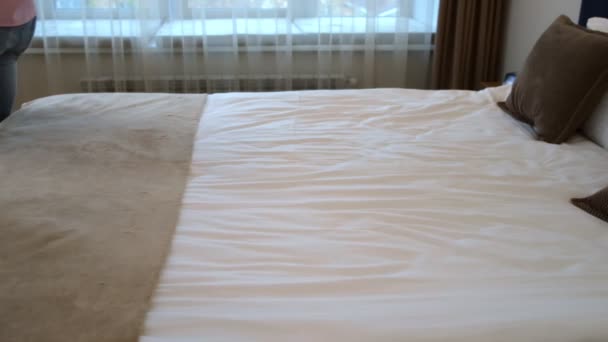 Happy young man and woman are falling on the bed in hotel room, slow motion. — Stock Video