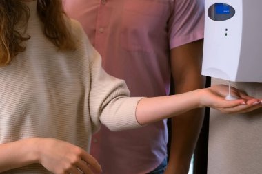 Kadın halka açık bir yerde otomatik alkolik dezenfektan kullanıyor..