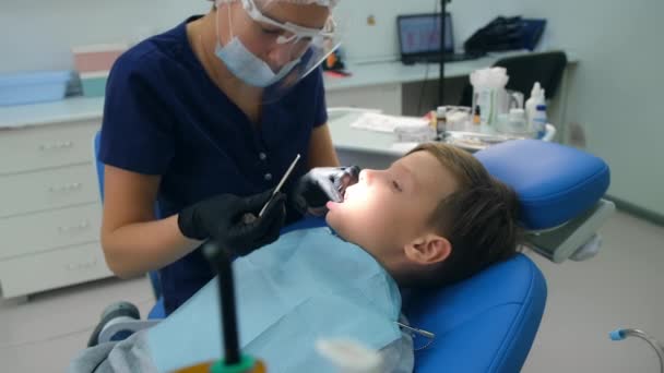 치과 의사들이 소년의 이를 보호하기 위해 청소를 한 후에 불소를 만들고 있다. — 비디오