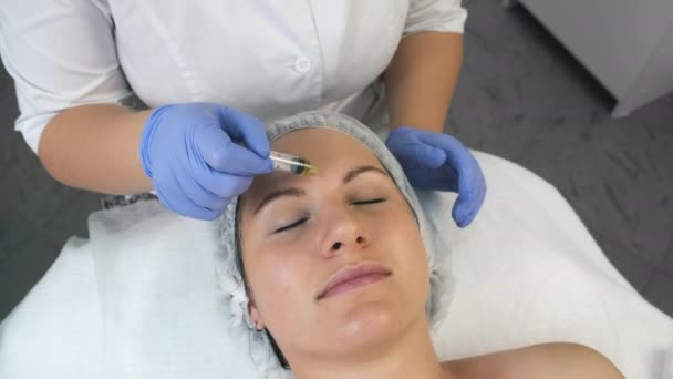Косметолог наносит желтую пилинг на лицо женщины в клинике красоты. — стоковое видео